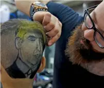  ?? AP ?? Muhannad Khaled Omar prepares an image of US President Donald Trump on the back of a customer’s head at his shop. —