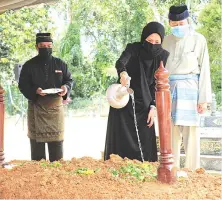  ??  ?? Tengku Permaisuri Norashikin (second, right) watering the grave of her father Abdul Rahman Baba, who was safely buried at the Shah Alam Royal Mausoleum yesterday. - Bernama photo