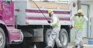  ??  ?? Workers wear protective gear against possible asbestos contaminat­ion in downtown Libby, Mont.