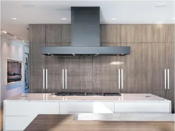  ?? PAUL STOPPI/DUNAGAN DIVERIO/THE ASSOCIATED PRESS ?? For this Miami Beach penthouse project, custom cladding on appliance fronts and cabinetry create an integrated sightline in this open-plan kitchen and living space.