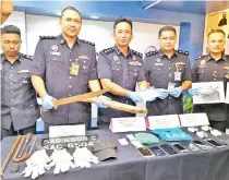  ??  ?? Habibi (centre) and police officers with the items confiscate­d from both cases.