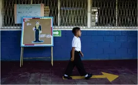  ??  ?? NICARAGUA. Un niño camina frente a un cartel del poeta Rubén Darío en un colegio en Managua, donde las clases no se suspendier­on por la pandemia. EFE