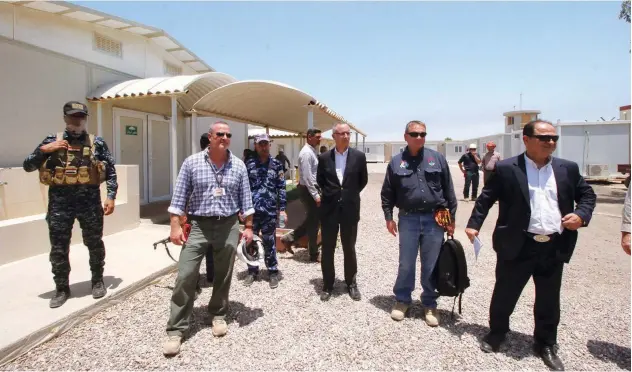  ?? Reuters ?? ↑ Iraqi security member stands guard next to Exxon’s staff and Iraqi oil officials of the West Qurna-1oilfield during the opening ceremony near Basra on Monday.