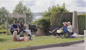  ?? ELAINE THOMPSON/AP ?? In this photo taken May 17, 2020, de Rham family members from the U.S. and Canada visit at the border between the countries in Peace Arch Park, in Blaine, Washington.