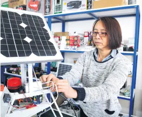  ??  ?? Ying Sarı connects a solar panel to a converter in her shop in Bingöl, Feb. 15, 2019.