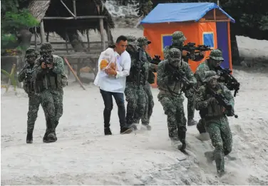  ?? Ted Aljibe / AFP / Getty Images ?? Philippine marines run as they simulate the rescue of a hostage as part of an amphibious raid and special-operations exercise by the navy at a marine training base in the town of Ternate in Cavite province.