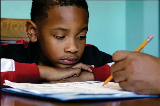  ?? (Ap/mark Humphrey) ?? Christian Ensrud, 7, watches Nov. 21 as his mother, Tamela Ensrud, help him with his homework at their home in Nashville, Tenn.