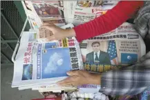  ?? AP photo ?? Business owner “Annie” weights down copies of the Chinese Daily News newspaper showcasing pictures of a suspected Chinese spy balloon, in the Chinatown district of Los Angeles on Sunday. The balloon’s presence in the sky above the United States before a military jet shot it down over the Atlantic Ocean with a missile Saturday has further strained U.S.- China ties.