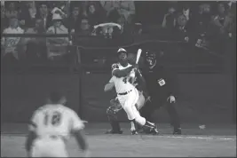  ?? HARRY HARRIS — THE ASSOCIATED PRESS FILE ?? The Atlanta Braves' Hank Aaron eyes the flight of the ball after hitting his 715th career homer in a game against the Los Angeles Dodgers in Atlanta on Monday night, April 8, 1974. Aaron broke Babe Ruth's record of 714 career home runs. Dodgers southpaw pitcher Al Downing, catcher Joe Ferguson and umpire David Davidson look on.