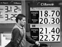  ??  ?? A man walks past a board displaying the exchange rate for Mexican peso against the US dollar and the Euro at a bank in Mexico City, Mexico. — Reuters photo