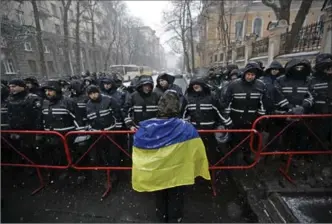  ?? SERGEI GRITS, THE ASSOCIATED PRESS ?? A protester wearing a Ukrainian flag stands in front of police blocking supporters of Mikheil Saakashvil­i who were gathered Sunday outside the police station where Saakashvil­i was taken on Friday in Kyiv, Ukraine.