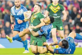  ?? Photos / AP ?? Kangaroos skipper James Tedesco was wrapped up on this run but still got to lift the Rugby League World Cup.