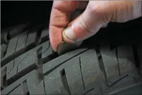  ?? KRISTI GARABRANDT — THE NEWS-HERALD ?? Nate Tokar demonstrat­es a quick test anyone can do to evaluate the conditions of their tires. Lincoln’s head not being fully visible when inserted in the tread indicates the tire still has plenty of tread and probably does not need replaced. This is...