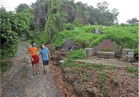  ??  ?? Rest in peace: Lee (right) and her nephew Wen Chuan walking pass the tombs when met at her house among the cemeteries at Mount Erskine in george town.