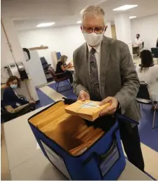  ??  ?? PLENTY MORE TO GO: A poll worker grabs the next batch of uncounted ballots.