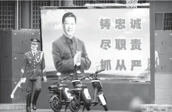  ?? MARK SCHIEFELBE­IN/AP ?? An honor guard member walks past a poster of Chinese leader Xi Jinping on Sept. 18 in Beijing.