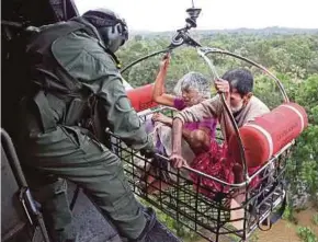  ??  ?? Flood victims are airlifted by Indian Navy soldiers during a rescue operation.