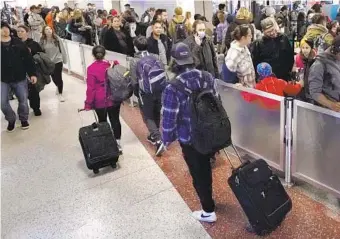  ?? CHARLES KRUPA AP ?? Travelers in Boston wheel their bags past the line for TSA screening in Terminal B at Logan Internatio­nal Airport on Monday. More than 2.6 million travelers were screened on Monday.