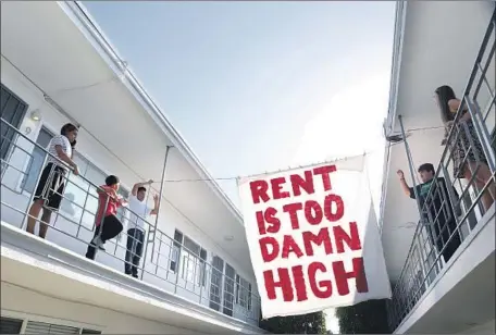  ?? Katie Falkenberg Los Angeles Times ?? ORGANIZERS WITH advocacy group Housing Long Beach hang a sign in the courtyard of a Cedar Avenue apartment complex last year. The California Legislatur­e narrowly passed a bill Wednesday to limit rent hikes statewide, the result of a deal brokered by the governor.