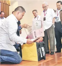  ??  ?? Nasri (left) goes through the checklist of items in the EC polling bag before heading off to SK Telok Melano, as Mohd Hisham (second right) looks on.