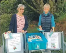  ??  ?? Bookends ambassador Sue Greenwood, left, tops up Barcaldine’s book bin, as Susan McIntyre arrives for a rake.