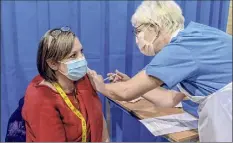  ?? Andrew Testa / New York Times ?? Gail Clayton, a nurse, receives the vaccine at the Cardiff and Vale Therapy Centre in Cardiff, Britain, on Dec. 8. Britain is allowing for a mix-and-match vaccine regimen.