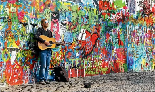  ?? ISTOCK ?? A young musician plays at the John Lennon wall in Prague.