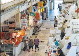  ?? Rebecca Blackwell The Associated Press ?? Customers walk through a partially open public market Friday in the Xochimilco district of Mexico City. The Mexican president’s push for a rapid restart of economic activity is not going over well with many local government­s.