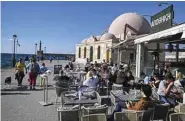  ?? ?? In this file photo tourists and locals sit at a restaurant cafe in the old town of Chania on Crete Island as the tourist season has started on the island. — AFP photos
