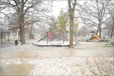  ?? Westside Eagle Observer/MIKE ECKELS ?? A light dusting of snow and sleet begins to accumulate on the ground at Field Kindley Park in Gravette Friday afternoon. Winter Storm Malcolm brought unexpected brief sleet and snow showers, in addition to high winds, to the Northwest Arkansas area.