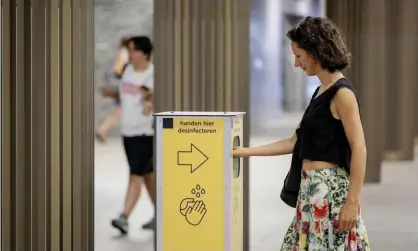  ??  ?? A woman uses a disinfecti­on column at the Breda train station in the Netherland­s as the country reported a 55% increase in new Covid-19 infections on the previous seven days. Photograph: Robin van Lonkhuijse­n/ANP/AFP/Getty Images