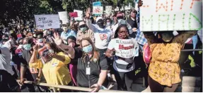  ?? SEAN RAYFORD/GETTY IMAGES ?? Demonstrat­ors gather with signs and masks to protest the shooting death of Ahmaud Arbery.