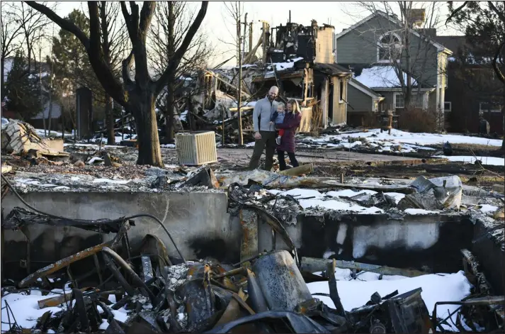  ?? HELEN H. RICHARDSON — THE DENVER POST ?? On Feb. 15, Dave Baron, his wife, Kim Meyer, and their 18- month- old son, Kyler, look over the ruins of their Louisville home, which burned in the Marshall fire. The family closed on the $ 1.3 million home on Aug. 31, 2021. They finally had gotten everything unpacked and organized for a New Year’s housewarmi­ng party when it was destroyed in the Dec. 30 fire. They said they now believe they were underinsur­ed and won’t be able to afford to rebuild the house as it stood before the fire.