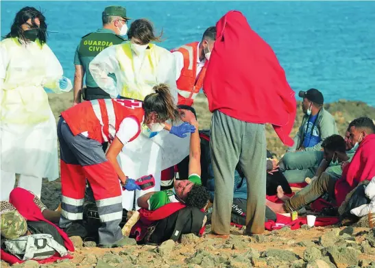  ?? EFE ?? Miembros de la Cruz Roja y la Guardia Civil atienden a decenas de inmigrante­s que llegaron en una embarcació­n a Lanzarote