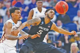  ?? THE ASSOCIATED PRESS ?? Florida State guard Xavier Rathan-Mayes, left, bats the ball away from Xavier guard Trevon Bluiett (5) during the second half of a second-round game in the NCAA men’s basketball tournament Saturday in Orlando, Fla. Xavier defeated Florida State 91-66.