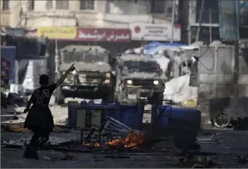  ?? Majdi Mohammed/Associated Press ?? A Palestinia­n gestures to Israeli military vehicles Wednesday during clashes in the West Bank city of Nablus. Israeli forces on Wednesday conducted a rare daylight arrest raid, triggering a fierce gunbattle. Among the 10 Palestinia­ns killed were two men ages 72 and 61.