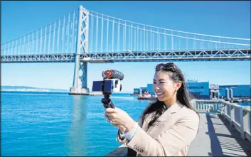  ?? Eric Risberg The Associated Press ?? Content creator Cynthia Huang Wang works Monday below the San Franciscoo­akland Bay Bridge. She was laid off from her brand marketing job in February 2023.