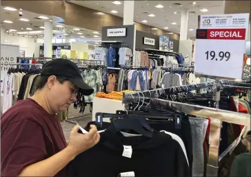  ?? NAM Y. HUH — THE ASSOCIATED PRESS ?? A customer checks price tags as she shops at a retail store in Schaumburg, Ill. Easing of retail hiring is happening in a labor market that has undergone volatile swings throughout the recovery from the pandemic recession.