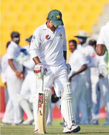  ?? AP ?? Sarfraz Ahmad walks back to the pavilion after being dismissed for 19 as Sri Lankan players celebrate during the fifth day of the first Test in Abu Dhabi yesterday.