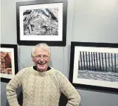  ?? CLIFFORD SKARSTEDT EXAMINER ?? Photograph­er Ken Powell stands next to his photograph­s on display at the Peterborou­gh Public Library for the annual Spark Photo Festival running until April 30.