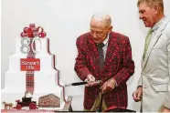  ?? Photo courtesy of Stewart Title ?? Stewart Morris Sr. cuts the cake at the celebratio­n while Stewart Morris Jr. looks on.