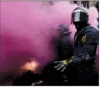  ?? AP/EMILIO MORENATTI ?? Catalan regional police officers stand amid smoke from a smoke bomb during clashes with independen­ce supporters trying to reach the Spanish government office Sunday in Barcelona, Spain.