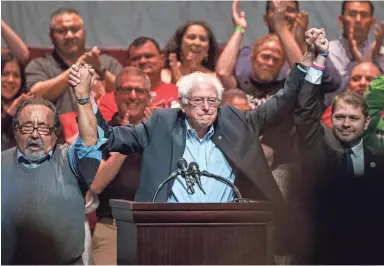  ?? SEAN LOGAN/THE REPUBLIC ?? Sen. Bernie Sanders holds hands with Congressma­n Raúl Grijalva and Congressma­n Ruben Gallego during a rally on Sunday at the Orpheum Theatre in Phoenix.