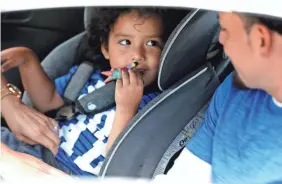  ?? ERIC SEALS/USA TODAY NETWORK ?? Ever Reyes Mejia of Honduras, looks as his 3-year-old son smiles at him while being buckled into a car seat. The two were reunited Tuesday in Grand Rapids, Mich., after being separated for three months.