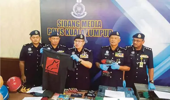  ?? PIC BY TEOH PEI YING ?? Kuala Lumpur police chief Datuk Seri Mazlan Lazim (centre) showing the T-shirt worn by the suspect in the MRT incident at the city police headquarte­rs yesterday.