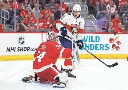  ?? RICK OSENTOSKI/USA TODAY SPORTS ?? Red Wings goaltender Alex Lyon makes a save in front of Panthers center Aleksander Barkov in the third period at Little Caesars Arena on March 2.