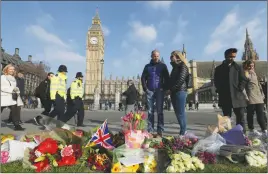  ?? AP PHOTO ?? People view floral tributes to victims of Wednesday’s attack outside the Houses of Parliament in London.