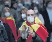  ?? REUTERS ?? A man wearing a protective face mask bangs saucepan lids as he attends a protest against the government in Madrid, Spain on Saturday.