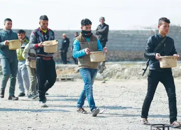  ?? (Khalid al Mousily/Reuters) ?? SUNNI ARAB fighters carry pots that are being made into improvised explosive devices to demolish homes belonging to Islamic State members in the south of Mosul, Iraq, last week.