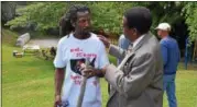  ??  ?? Dahmeek McDonald’s uncle, Messiah Cooper, stands to the left while speaking with Pastor Jackie Robinson during a community barbecue hosted by Cooper after his nephew was recently involved in an officer-involved shooting.